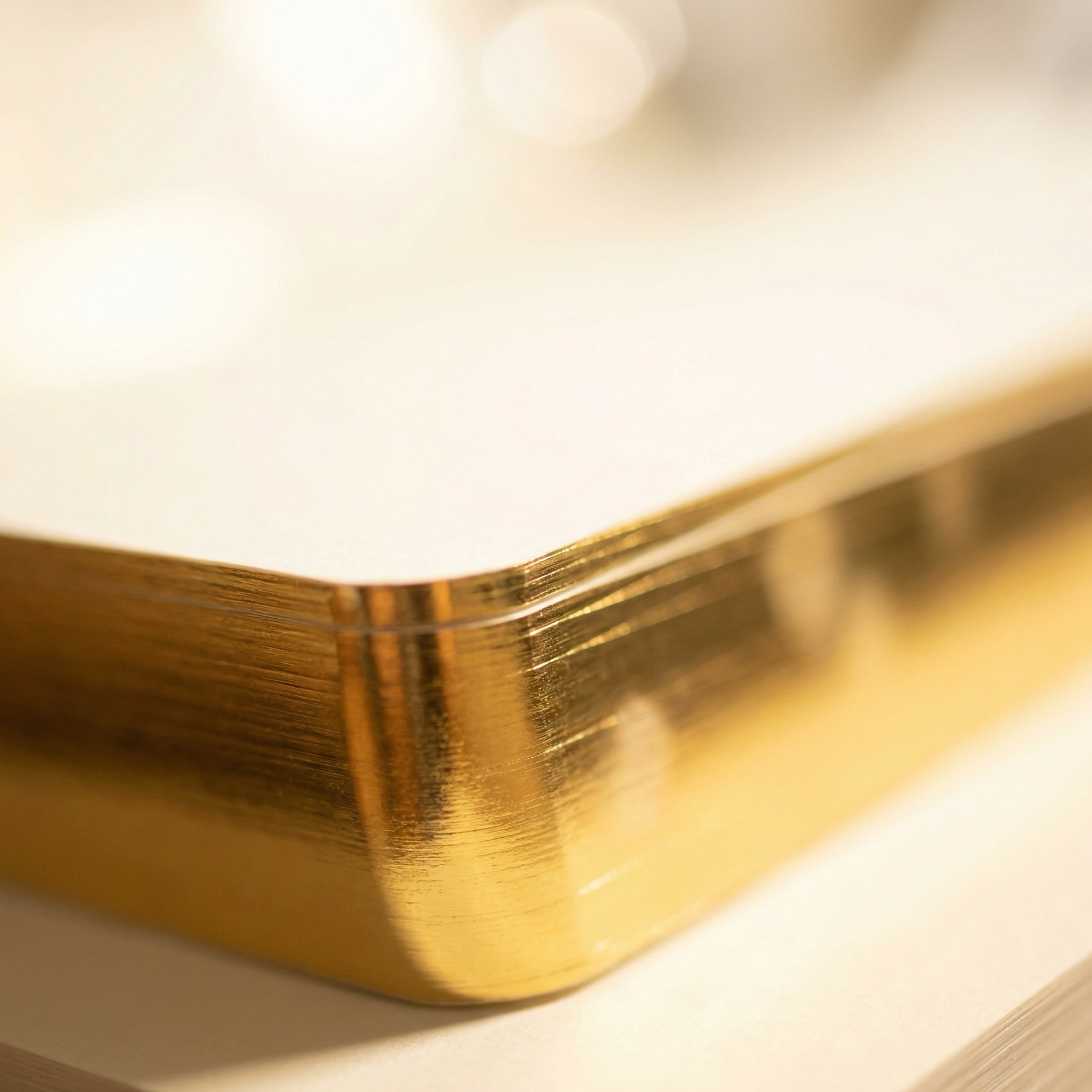 Macro detail of a gold foil edge on a cream paper stack.
