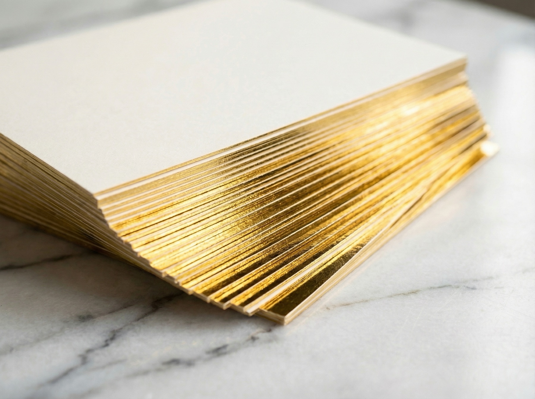 A close view of stacked pieces with bright gold foil edges on a marble surface.