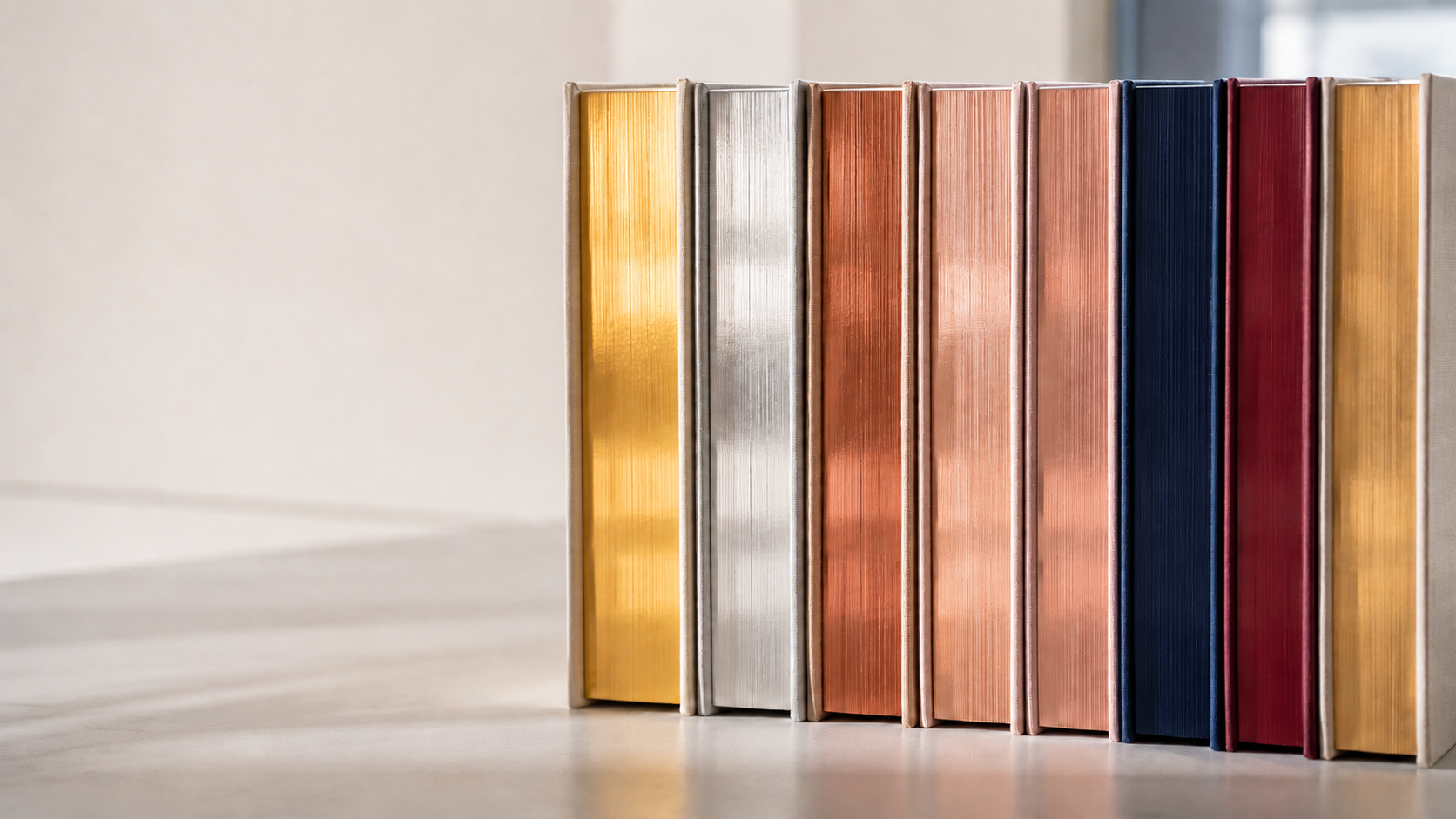 Contemporary hardcover books with gold, silver, copper, rose-gold, navy, and burgundy finished edges.